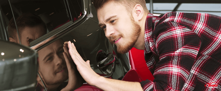 NCC-Handsome bearded male customer examining car paint on a new auto at the dealership
